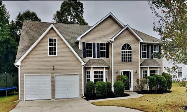 view of front of home featuring a front lawn, a garage, and a trampoline