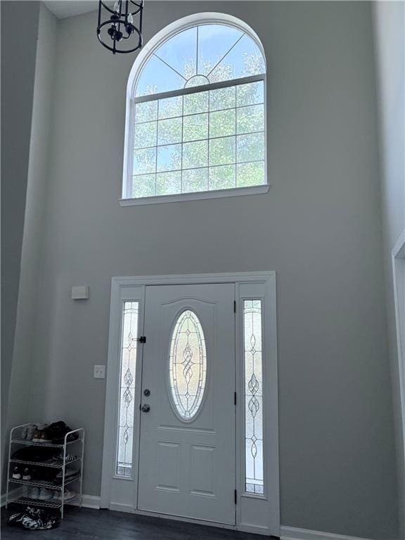 entrance foyer featuring dark wood-type flooring, plenty of natural light, and an inviting chandelier