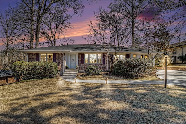 ranch-style home featuring a front yard and brick siding