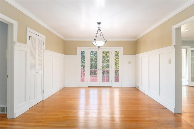 spare room with light wood finished floors, a decorative wall, crown molding, and french doors