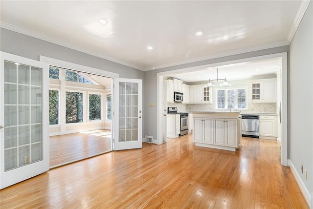 kitchen featuring glass insert cabinets, stainless steel appliances, light countertops, white cabinetry, and pendant lighting