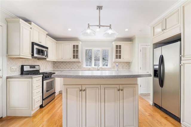 kitchen with glass insert cabinets, stainless steel appliances, light countertops, and a center island