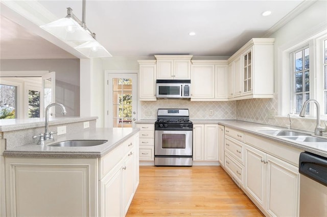 kitchen featuring a sink, stainless steel appliances, light countertops, and glass insert cabinets