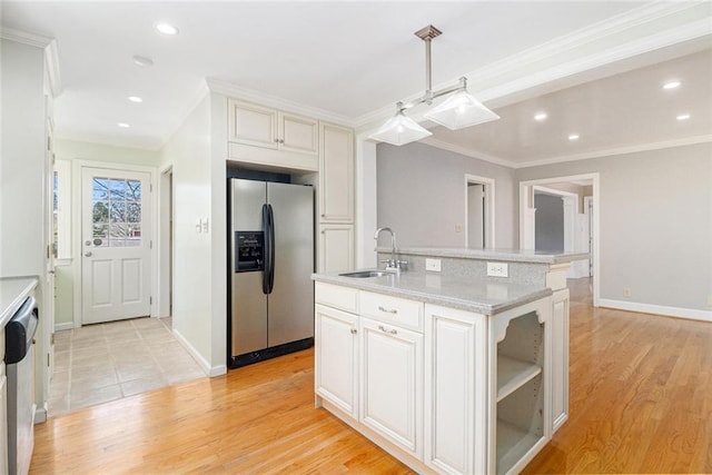 kitchen with a sink, white cabinetry, light wood-style floors, appliances with stainless steel finishes, and a center island with sink