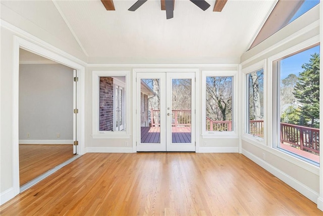 unfurnished sunroom with a healthy amount of sunlight, ceiling fan, vaulted ceiling, and french doors