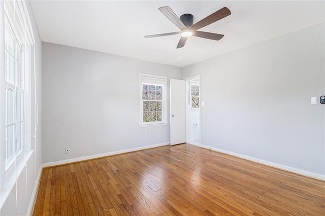 unfurnished room featuring a ceiling fan, hardwood / wood-style flooring, and baseboards