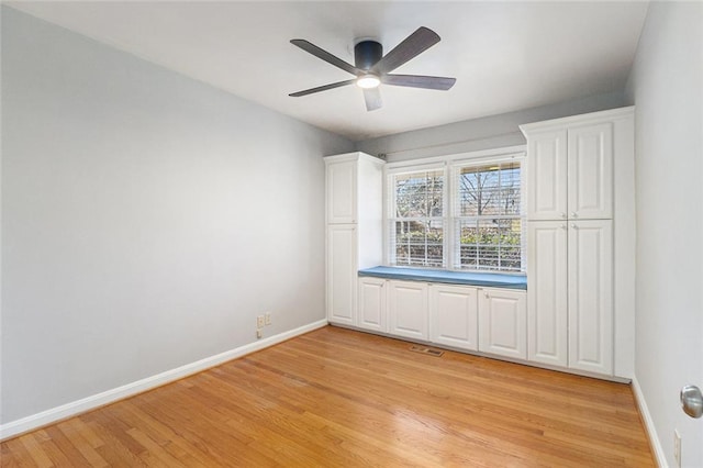 empty room featuring ceiling fan, light wood-type flooring, visible vents, and baseboards