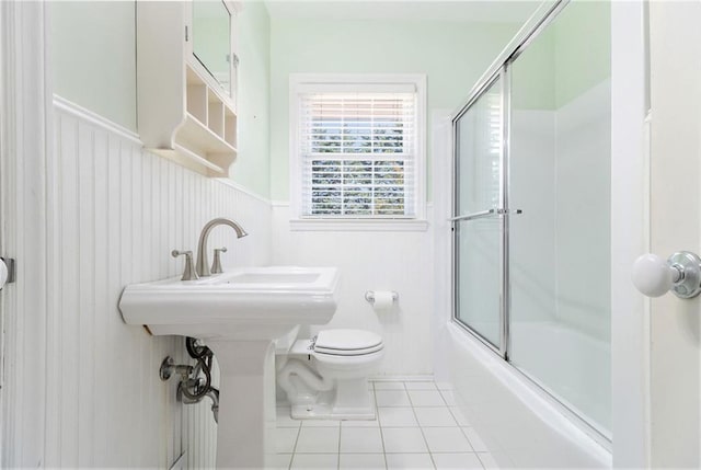 bathroom featuring toilet, shower / bath combination with glass door, and tile patterned flooring