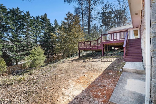 view of yard featuring a deck, fence, and stairway