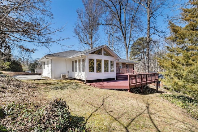 exterior space featuring a deck, a lawn, and a sunroom