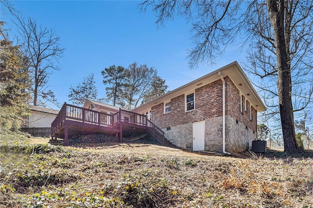 back of house featuring cooling unit, brick siding, stone siding, stairway, and a wooden deck