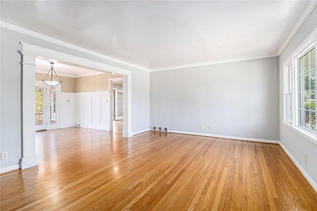 empty room featuring light wood-style floors, a wealth of natural light, and crown molding