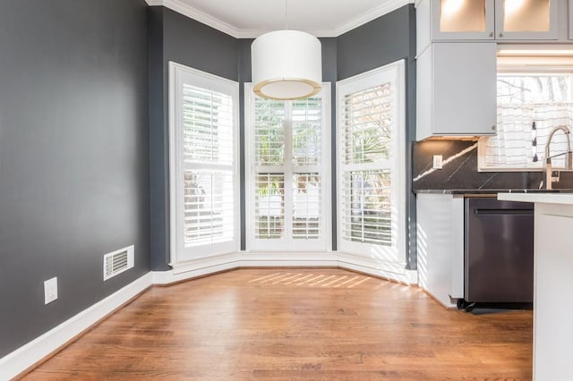 unfurnished dining area featuring hardwood / wood-style flooring and crown molding