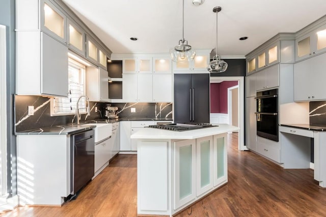 kitchen with a kitchen island, wood-type flooring, stainless steel appliances, and hanging light fixtures