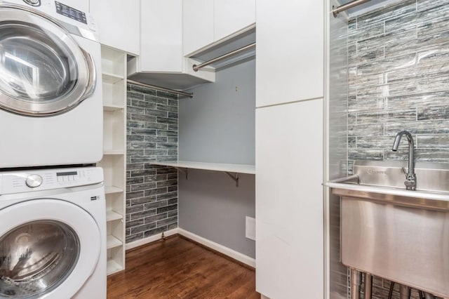 clothes washing area featuring stacked washer and dryer and dark hardwood / wood-style floors