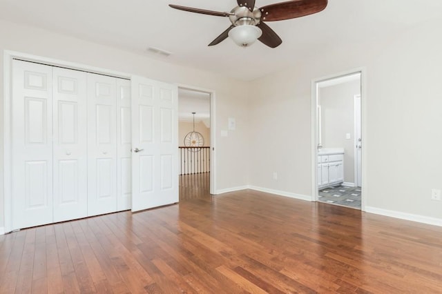 unfurnished bedroom featuring ensuite bathroom, ceiling fan, wood-type flooring, and a closet