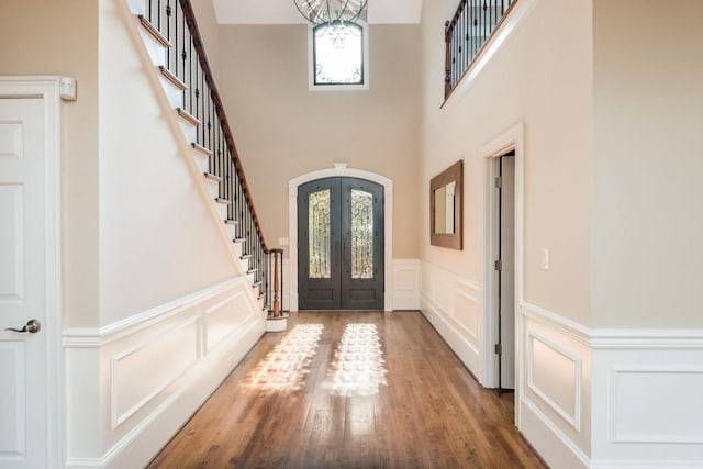 foyer entrance with french doors, a high ceiling, a notable chandelier, and hardwood / wood-style flooring