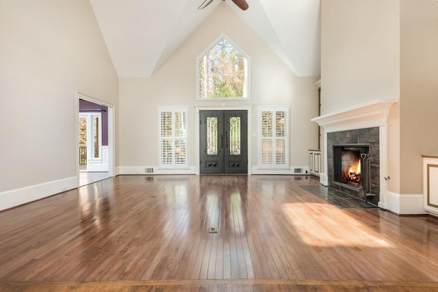 foyer entrance with french doors, dark hardwood / wood-style flooring, ceiling fan, high vaulted ceiling, and a fireplace