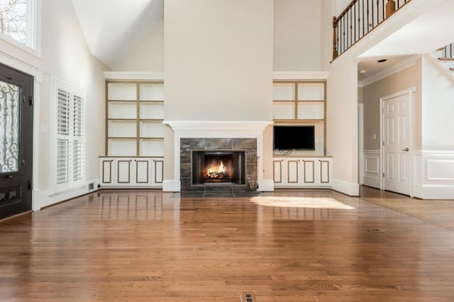 unfurnished living room featuring a fireplace, wood-type flooring, and a towering ceiling