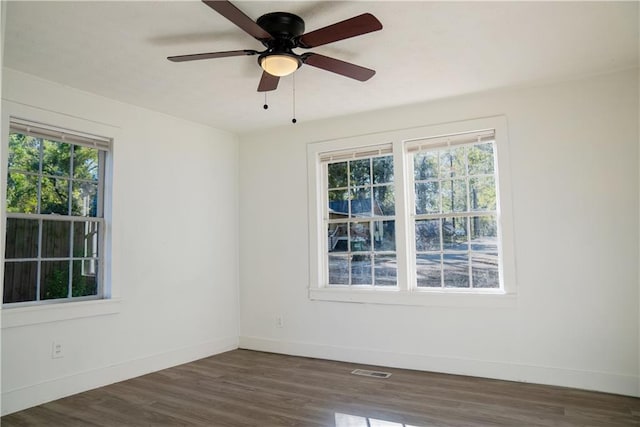 empty room with ceiling fan, a healthy amount of sunlight, and dark hardwood / wood-style floors