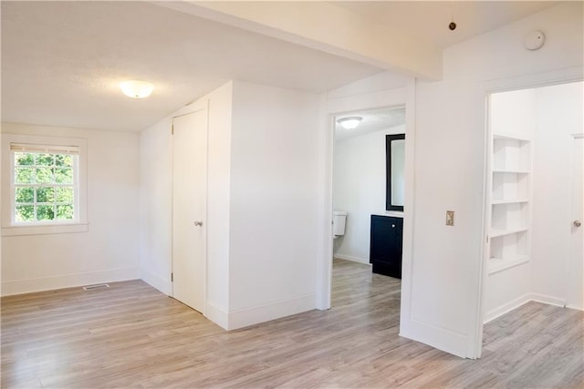 empty room featuring light wood-type flooring and vaulted ceiling