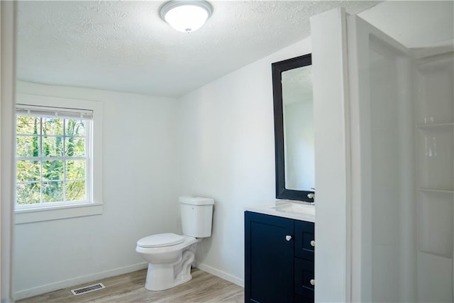 bathroom with hardwood / wood-style flooring, vanity, toilet, and a textured ceiling