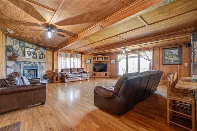 living room featuring wood-type flooring, ceiling fan, and wood walls