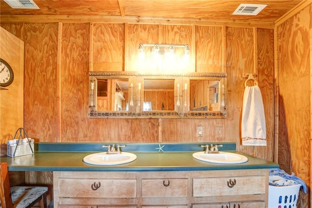 bathroom with dual sinks, wood walls, and large vanity