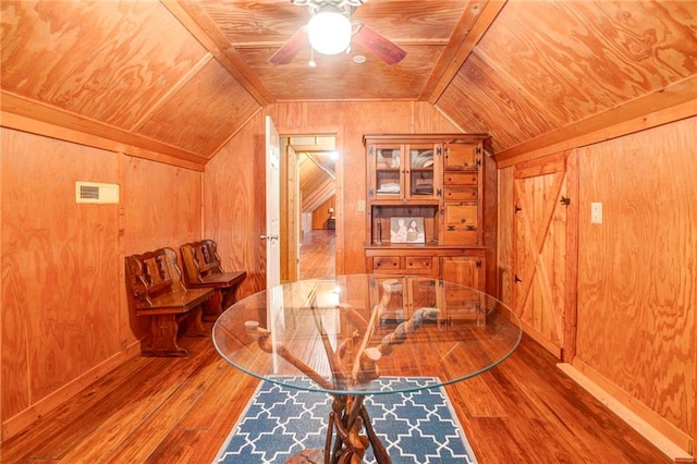 interior space with ceiling fan, vaulted ceiling, wood-type flooring, wood walls, and wooden ceiling