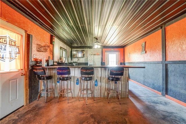 bar featuring ceiling fan, concrete floors, and white refrigerator