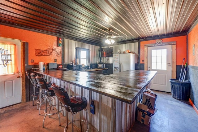 kitchen with ceiling fan, white fridge with ice dispenser, a healthy amount of sunlight, and kitchen peninsula