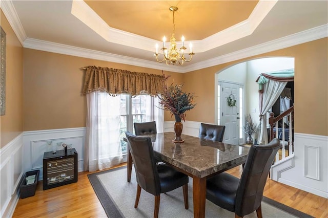 3780 Summit Gate Dr, Suwanee, GA 30024 - dining space with a wainscoted wall, a chandelier, light wood-style floors, arched walkways, and ornamental molding