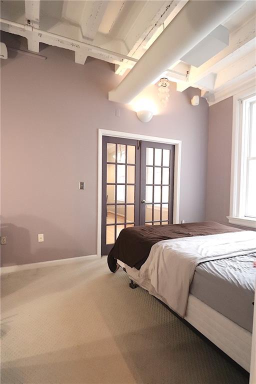 bedroom with beamed ceiling, carpet, and french doors