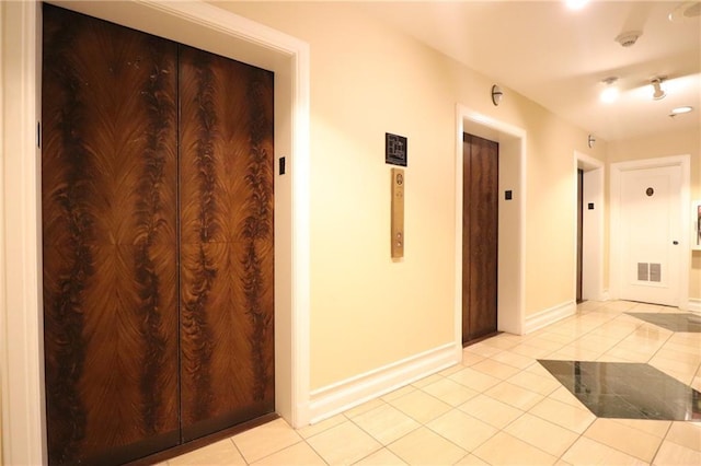 hallway featuring light tile patterned floors and elevator