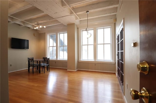 dining area featuring beam ceiling and light hardwood / wood-style flooring