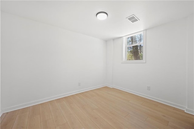 empty room featuring light wood-style floors, visible vents, and baseboards