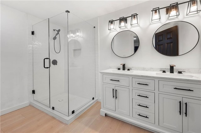 full bathroom with double vanity, wood finished floors, a sink, and a shower stall