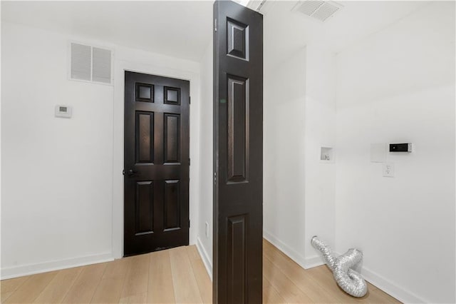 interior space featuring laundry area, visible vents, light wood-style flooring, and baseboards