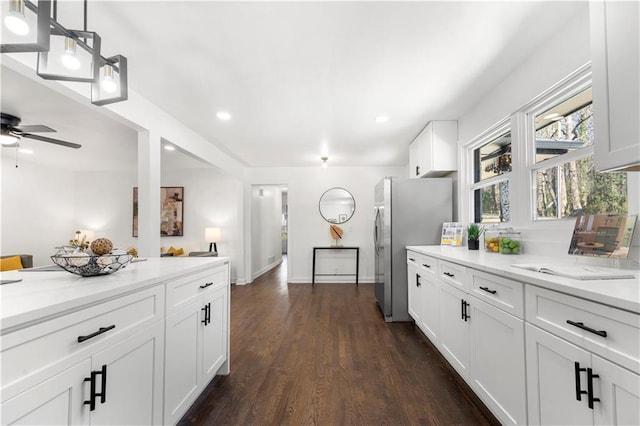 kitchen with decorative light fixtures, stainless steel refrigerator, dark hardwood / wood-style flooring, light stone countertops, and white cabinets