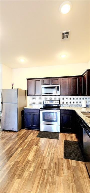 kitchen featuring tasteful backsplash, visible vents, light wood finished floors, and stainless steel appliances