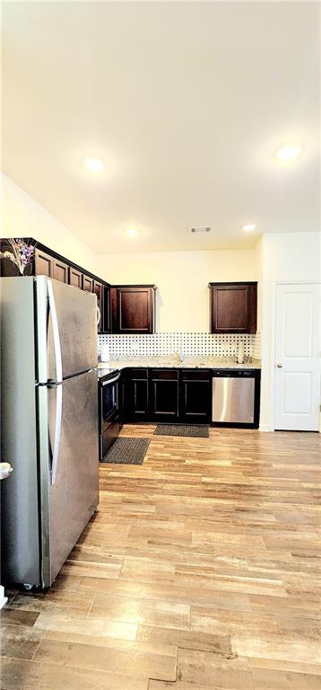 kitchen featuring light wood-style flooring, tasteful backsplash, recessed lighting, dark brown cabinetry, and appliances with stainless steel finishes