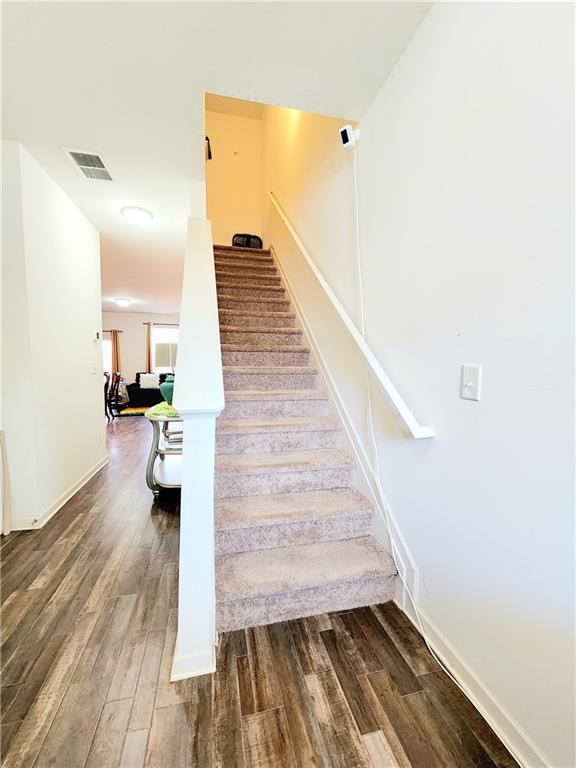 staircase with wood finished floors, visible vents, and baseboards