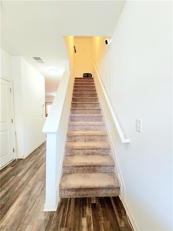 stairway featuring visible vents, baseboards, and wood finished floors