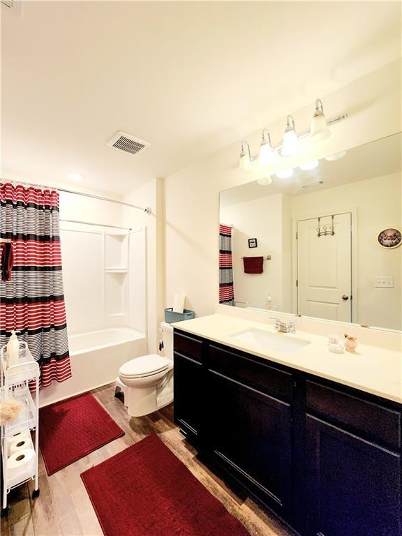 full bath with visible vents, toilet, wood finished floors, and vanity