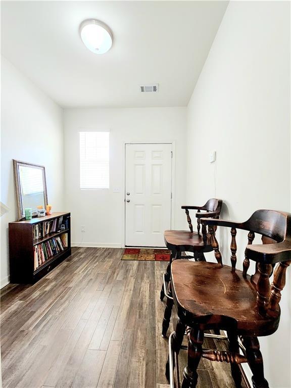 living area featuring visible vents, baseboards, and wood finished floors