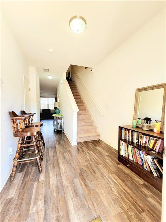 living area with stairs, wood finished floors, and visible vents