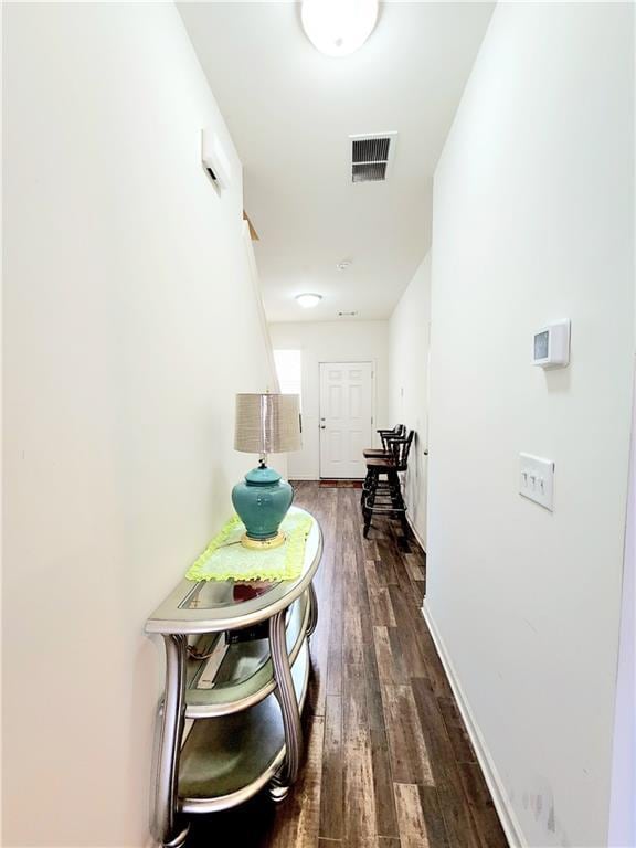 hall featuring dark wood-style floors, visible vents, and baseboards