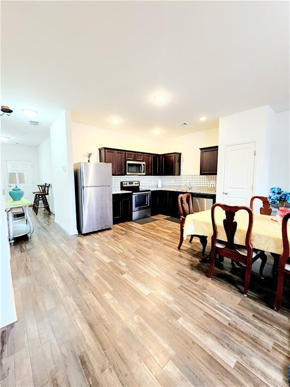 kitchen featuring dark brown cabinets, light wood-type flooring, decorative backsplash, recessed lighting, and stainless steel appliances