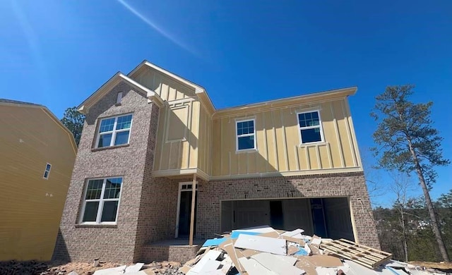 view of front of house featuring a garage, brick siding, and board and batten siding