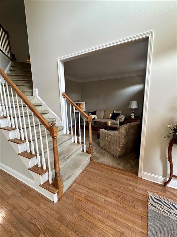 staircase with wood-type flooring and ornamental molding